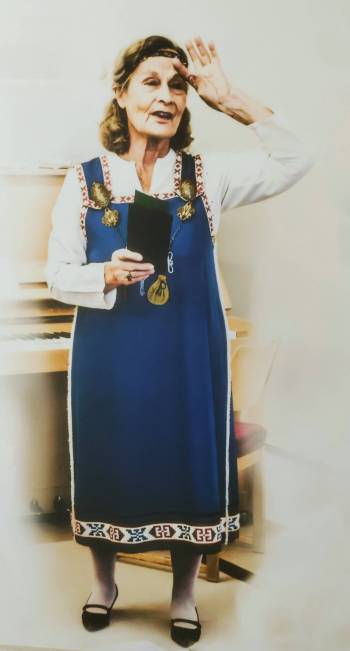 Nainen vaalealla taustalla kansallispuku yllään